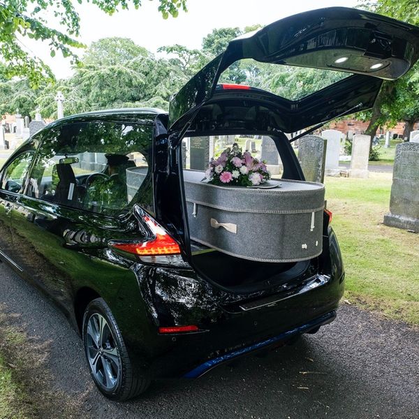 Funeralcare Nissan Electric Hearse, Black, Still shot, Back three quarter angle, in graveyard
